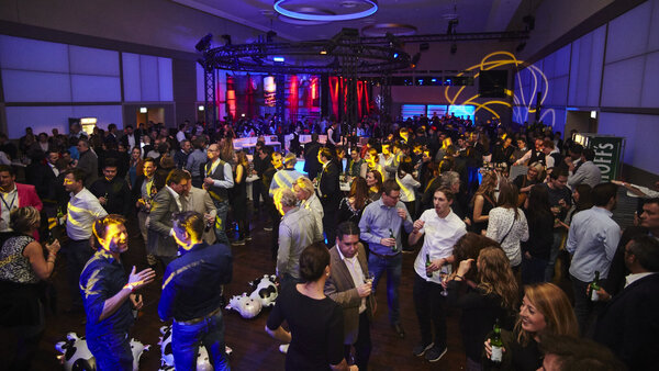 Party im Goldsaal mit zentraler runder Bar und blau-roter Partybeleuchtung.