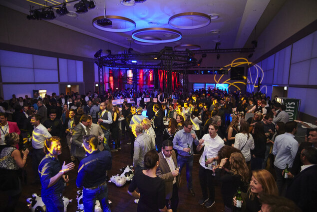 Party im Goldsaal mit zentraler runder Bar und blau-roter Partybeleuchtung.