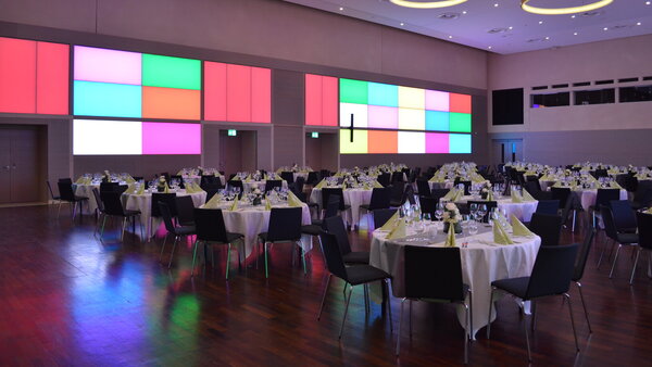 Festlich gedeckter Goldsaal mit Galabestuhlung und bunter Wandbeleuchtung.