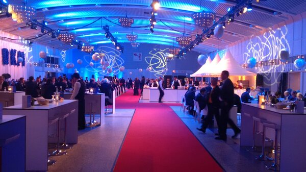 Get-together in Halle 1 mit Stehtischen, Tanzfläche und atmosphärischer Beleuchtung.