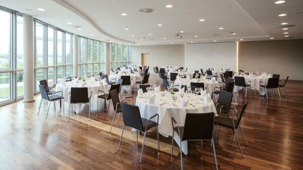 Festlich gedeckter Saal 8 mit runden Tischen und Blick auf den Rosengarten.